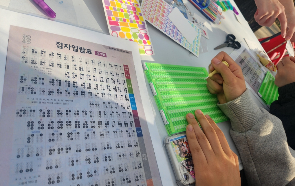 Students punching out braille to make bookmarks of their own